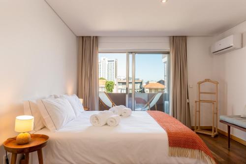 1 dormitorio con 1 cama blanca grande y toallas. en Sunny Loft in Downtown Porto with Private Parking, en Oporto