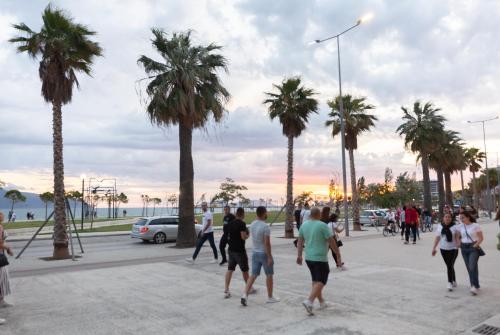 een groep mensen die door een straat met palmbomen lopen bij Porta Apartament in Vlorë