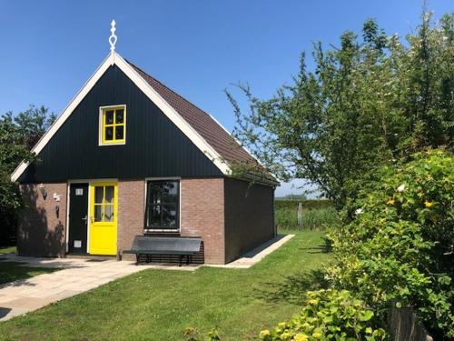 a black and yellow house with a bench in the yard at House on park "Zijper Eilant" in Oudesluis
