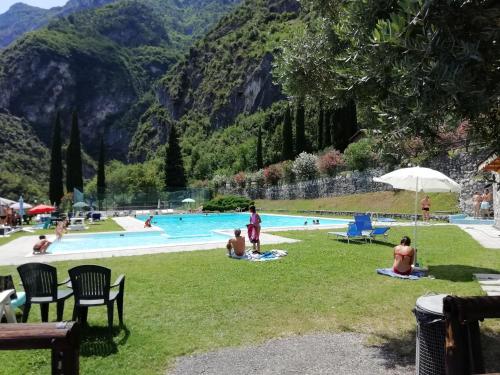 un grupo de personas sentadas en el césped junto a una piscina en LAKE & CASTLE VIEW apartment, en Riva del Garda