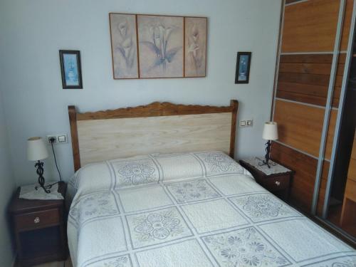 a bedroom with a bed with two nightstands and two lamps at Les Viesques in Colunga