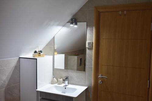 een badkamer met een wastafel, een spiegel en een deur bij Mountain Residence Zlatibor - Apartman Sara 1 in Zlatibor