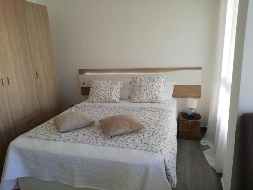 1 dormitorio con 1 cama blanca y 2 almohadas en Pitaya en Algarrobo-Costa