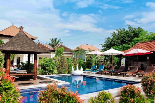 - une piscine dans un complexe avec des chaises et des parasols dans l'établissement Uluwatu Jungle Villa, à Uluwatu