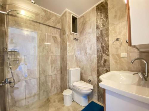 a bathroom with a toilet and a sink and a shower at Nur Suites & Hotels in Kalkan