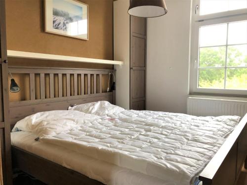 - une chambre avec un grand lit blanc et une fenêtre dans l'établissement Haus Meerliebe, Whg 2, à Cuxhaven