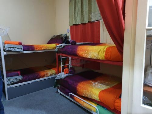 um quarto com 4 beliches e cobertores coloridos em Golden Mt Rest on James em Mount Morgan