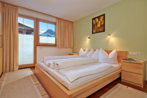 1 dormitorio con 1 cama grande con almohadas blancas en Apart Sunshine, en Längenfeld
