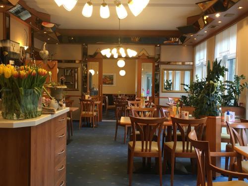 a restaurant with wooden chairs and tables and flowers at Café Feldmann & Pension in Bad Sooden-Allendorf