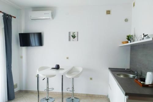 una cucina con due sgabelli bianchi e un lavandino di Apartments Vanda a Rovigno (Rovinj)