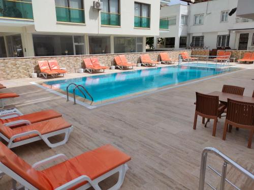 a swimming pool with orange chairs and tables and chairs at Altinersan Hotel in Didim