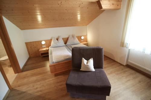 a attic room with two beds and a chair at Apartements Richlegghof in Filzmoos