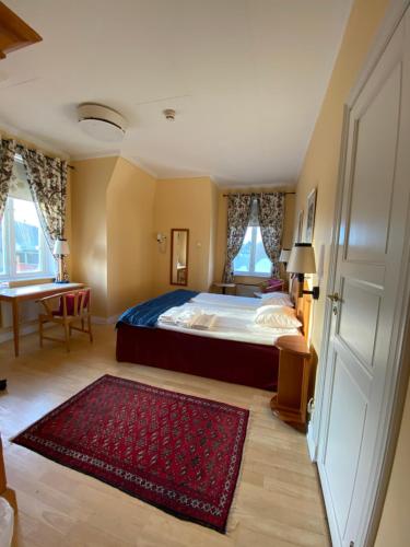 a bedroom with a large bed and a red rug at Broby Gästgivaregård in Sunne