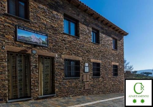a brick building with a television on the side of it at Casa Rural Al-Mofrag y Apartamentos El Mirador de Monfragüe in Villarreal de San Carlos