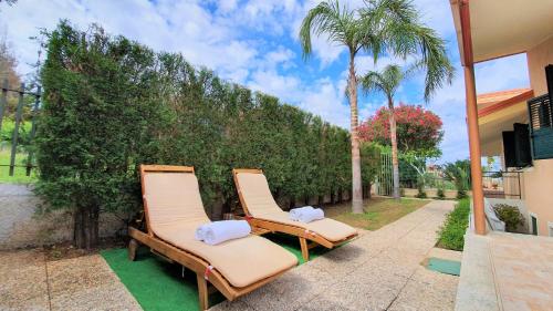 - deux chaises longues sur une terrasse avec des palmiers dans l'établissement Villa Paglianiti - Your FAMILY Residence!, à Briatico