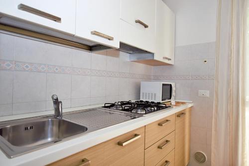 eine Küche mit einer Spüle und einem Herd in der Unterkunft Residenza Canova in Lignano Sabbiadoro