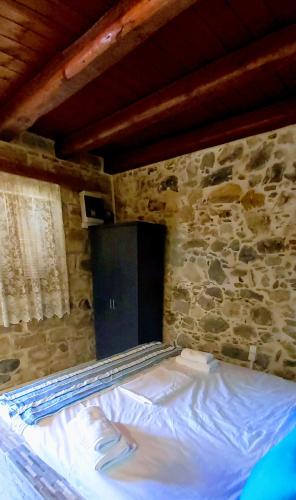 a bed in a room with a stone wall at Mariaeva Rooms in Léntas