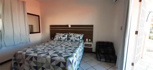 a bedroom with a bed with a blue and white comforter at Parada dos Golfinhos in Florianópolis