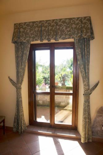 a glass door with curtains in a room at Casale san Pietro in Otricoli