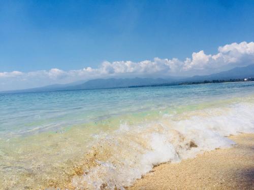 a body of water with a wave in the sand at Alibaba Bungalows in Gili Air