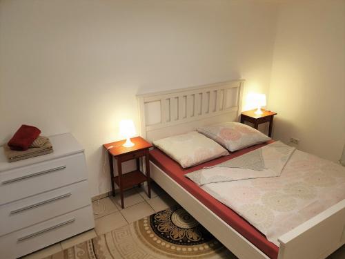 a small bedroom with two night stands and a bed at Moderne Einliegerwohnung AMARA - Friedrichshafen am Bodensee in Friedrichshafen