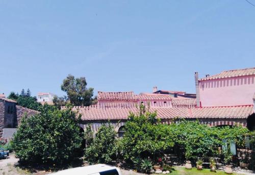 un groupe de bâtiments aux toits rouges et aux arbres dans l'établissement Il Portico Guesthouse, à Muravera