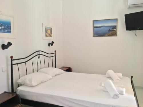 a bedroom with a bed with white sheets and a tv at Camelia Studios in Yenion