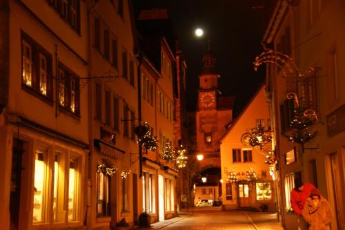 uma mulher a andar pela rua à noite em Hotel Sonne - Das kleine Altstadt Hotel em Rothenburg ob der Tauber