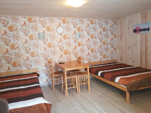 a room with a bed and a table and a wall with roses at Poilsiavietė Mano Maljorka in Šventoji