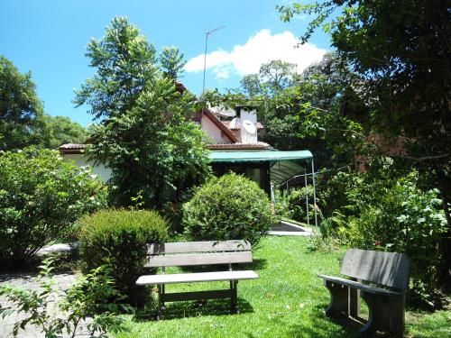 dos bancos sentados en el césped frente a una casa en Ex Pousada Vale do Bosque - Aluguel por temporada, en Gramado