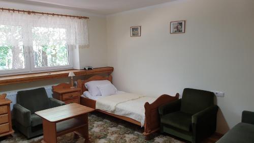 a bedroom with a bed and two chairs and a table at Villa Maniszewo in Serbów