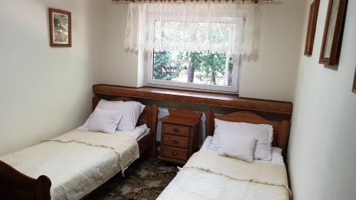 2 camas individuales en una habitación con ventana en Villa Maniszewo, en Serbów
