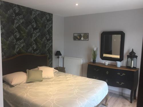 - une chambre avec un lit avec un miroir et une commode dans l'établissement Côté jardin des Charmilles, à Quettehou