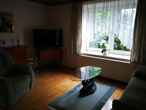 un salon avec une table en verre devant une fenêtre dans l'établissement Ferienwohnung Danziger, à Celle