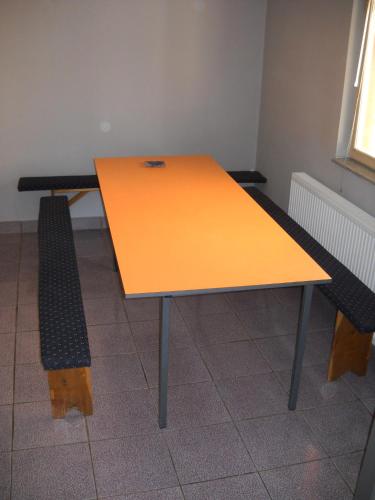 an orange table and a bench in a room at Prenociste DUGA in Užice