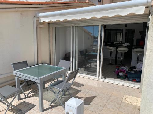 une table et des chaises en verre sur la terrasse dans l'établissement MARINA LOVE, au Cap d'Agde