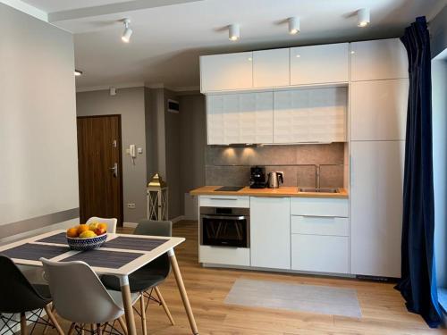 a kitchen with white cabinets and a table and chairs at Apartamenty Silence Baltic Indygo in Pobierowo