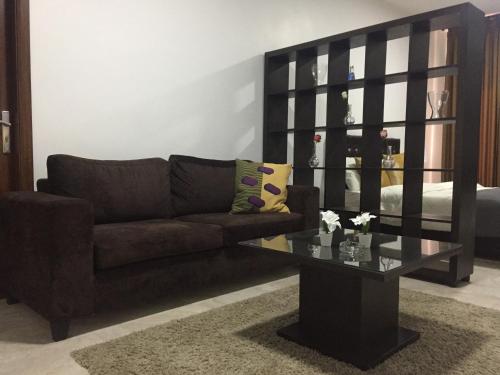 a living room with a brown couch and a glass table at Tunaib Plaza in Aţ Ţunayb