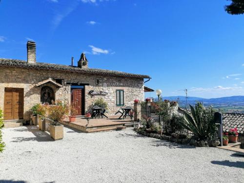 ein Steinhaus mit einer Terrasse und einem Tisch in der Unterkunft Camere da Anna Maria in Assisi