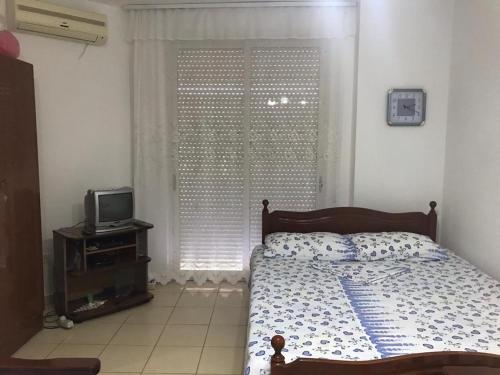 - une chambre avec un lit, une télévision et une fenêtre dans l'établissement Geni Apartment, à Durrës