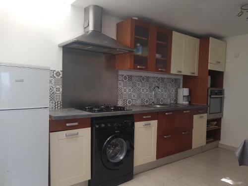 une cuisine avec une cuisinière et une machine à laver dans l'établissement Appartement calme lumineux face a la mer, à Sète