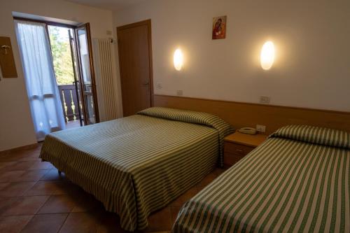 a hotel room with two beds and a window at Casa Santa Maria in Folgaria