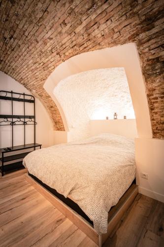 un lit dans une chambre avec un mur de briques dans l'établissement Les Voûtes du Vieux-Port, à Marseille