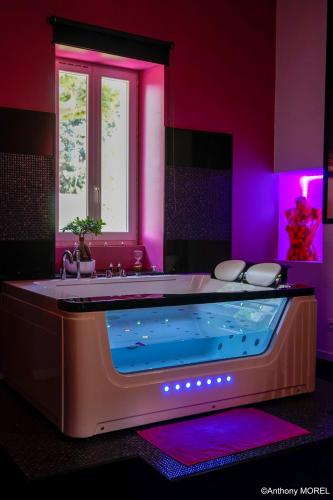 a bathroom with a large tub with purple lighting at Désir'ôôm in Cabannes