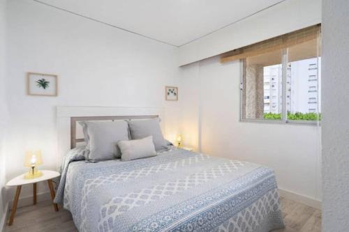 ein weißes Schlafzimmer mit einem Bett und einem Fenster in der Unterkunft APARTAMENTO ROMA XI in Playa de Gandia