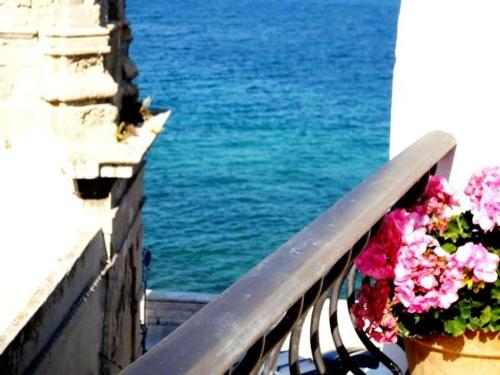a bench with flowers on it next to the water at Anna's Rose Holiday Home in Monopoli