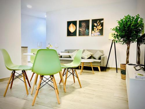 a dining room with green chairs and a table at Apartamentos Villas Romanas in Mérida