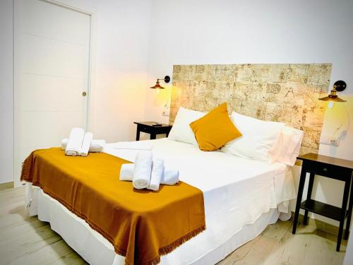 a bedroom with a large white bed with towels on it at Apartamentos Villas Romanas in Mérida