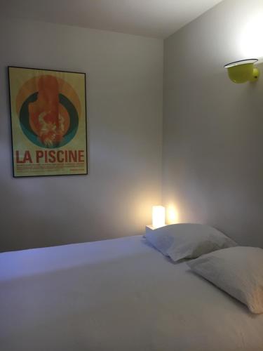 a bedroom with a white bed with a picture on the wall at T2 L'Escapade in La Ciotat