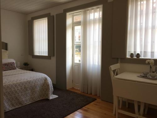 um quarto com uma cama, uma secretária e janelas em Vila Baixa - alojamento local em Guimarães
